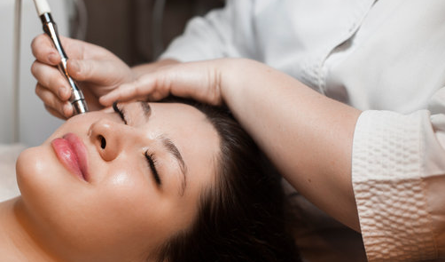 Facial treatment with a handheld beauty device on a reclining client