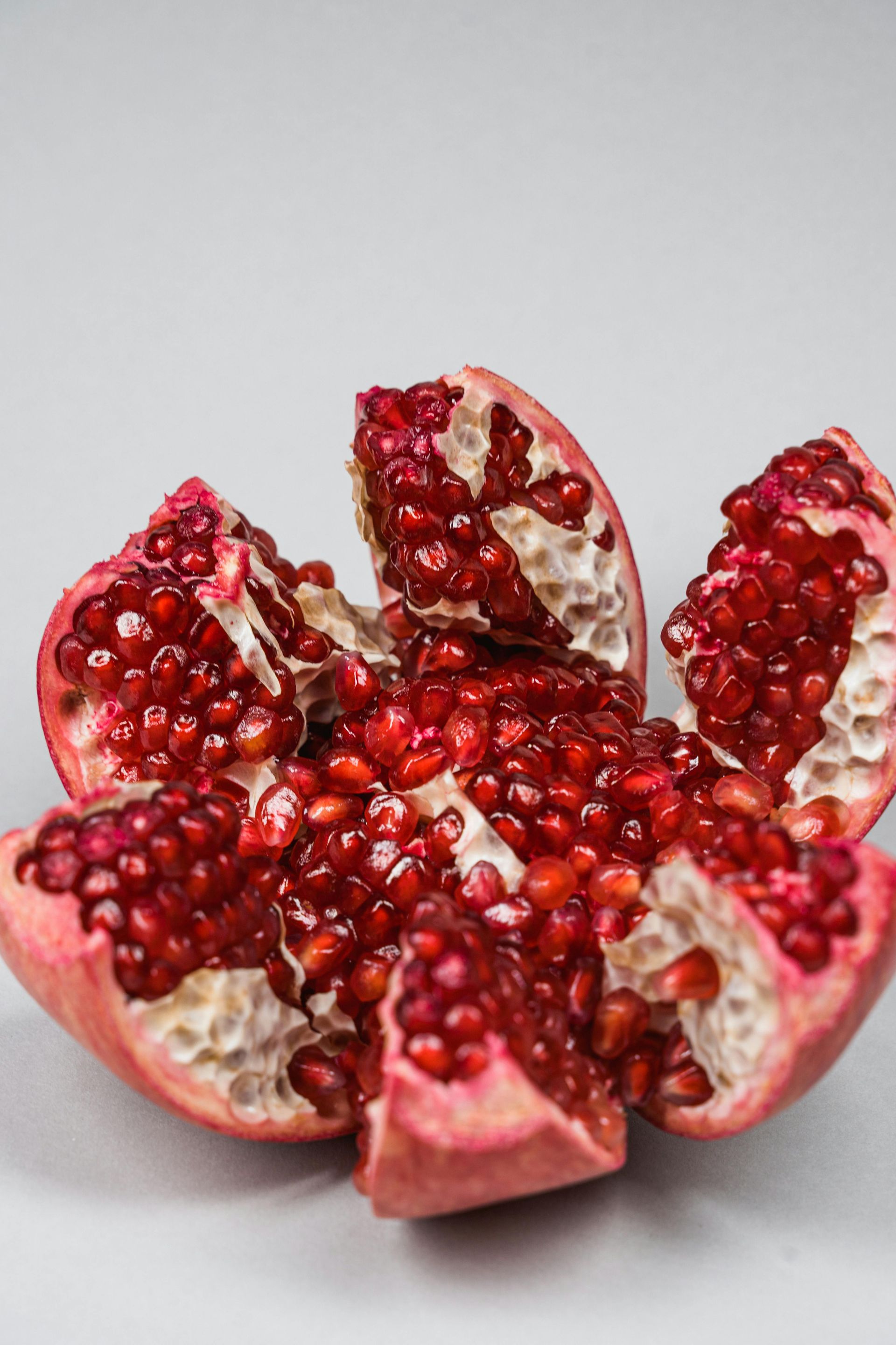 A pomegranate is cut in half and sitting on a table.