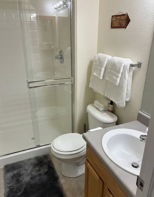 Professionally cleaned guest bathroom in Fountain, CO featuring a full shower, wooden vanity, and fresh high-quality towels for large groups and sports teams staying near Colorado Springs.