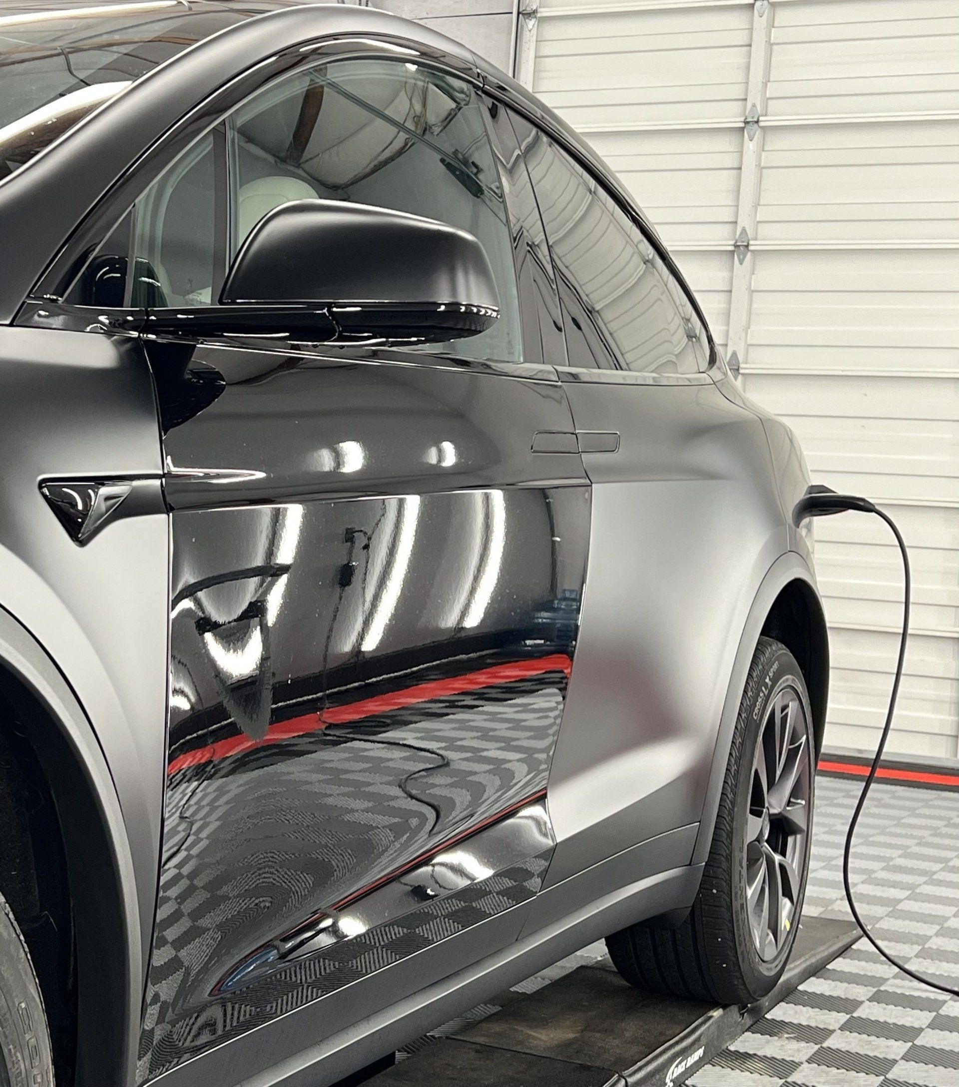 A tesla model x is being charged in a garage