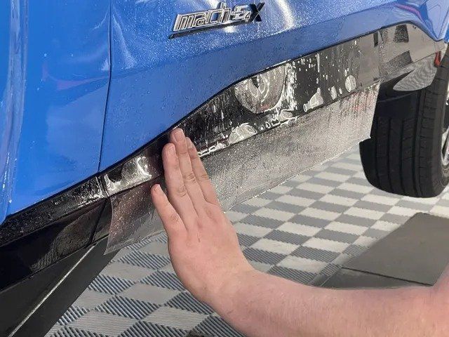 A person is touching the side of a blue car.
