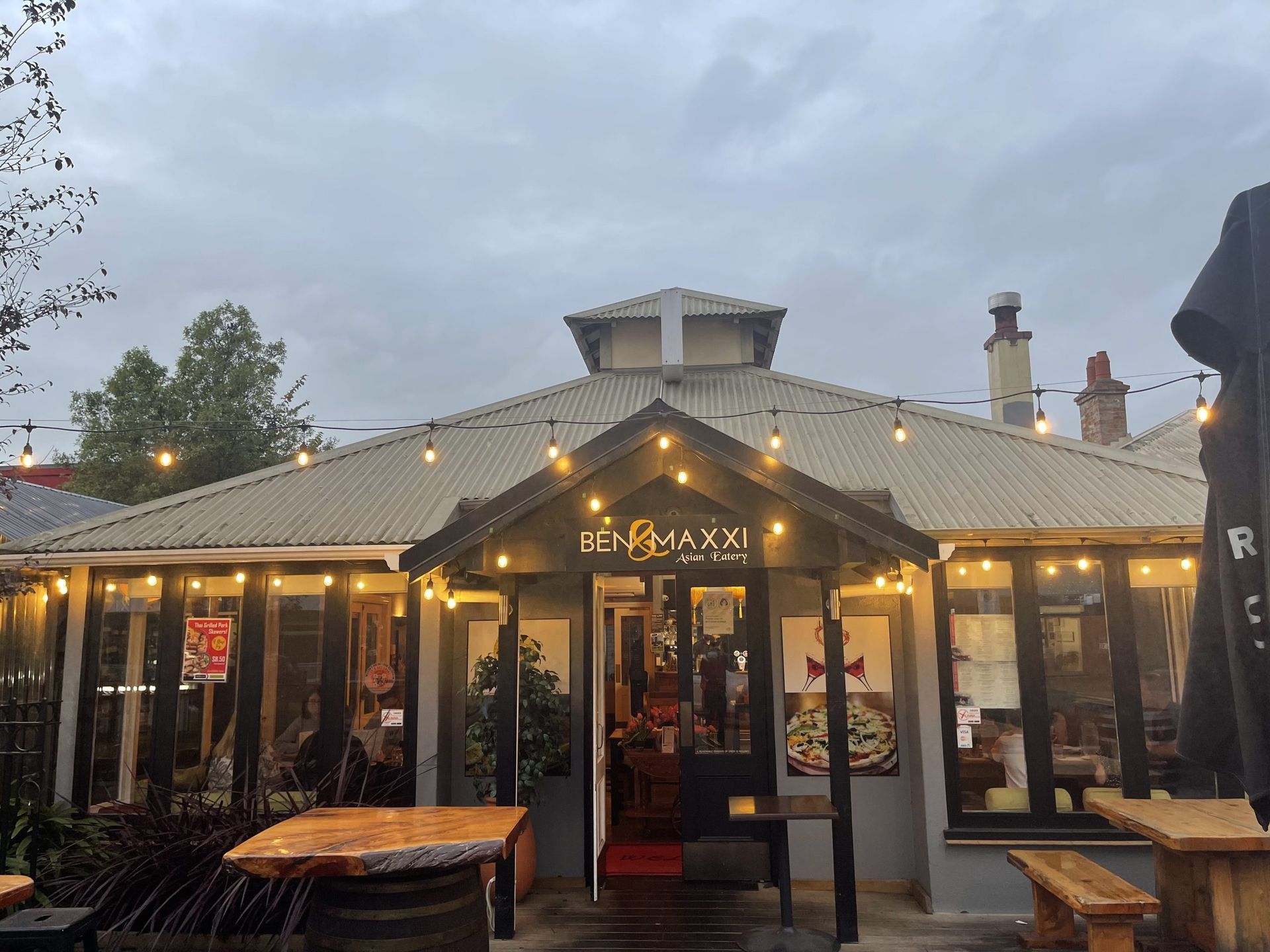 A restaurant with tables and umbrellas in front of it