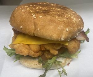 A close up of a chicken sandwich with cheese and lettuce on a bun.