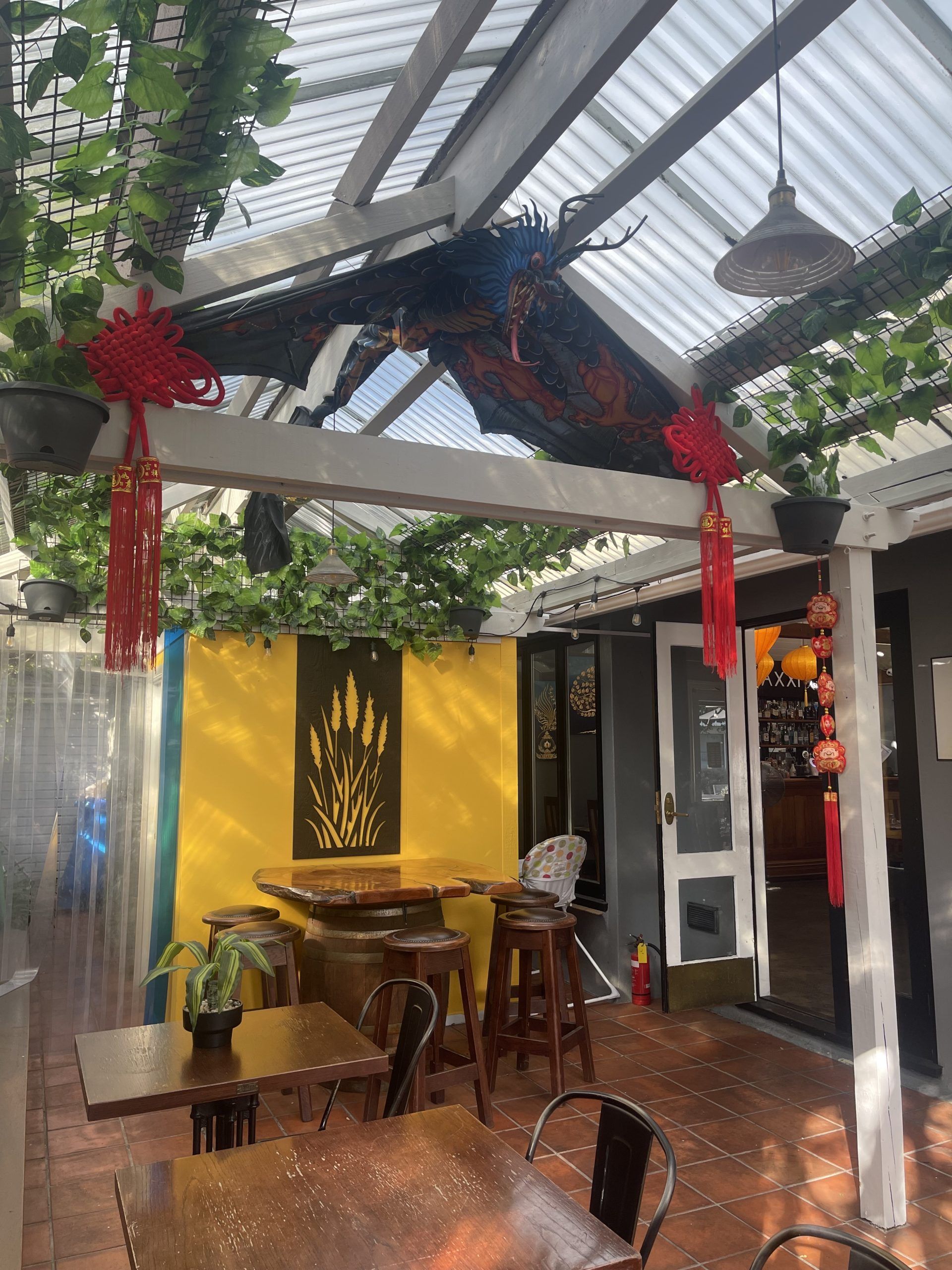 A restaurant with tables and chairs under a clear roof.