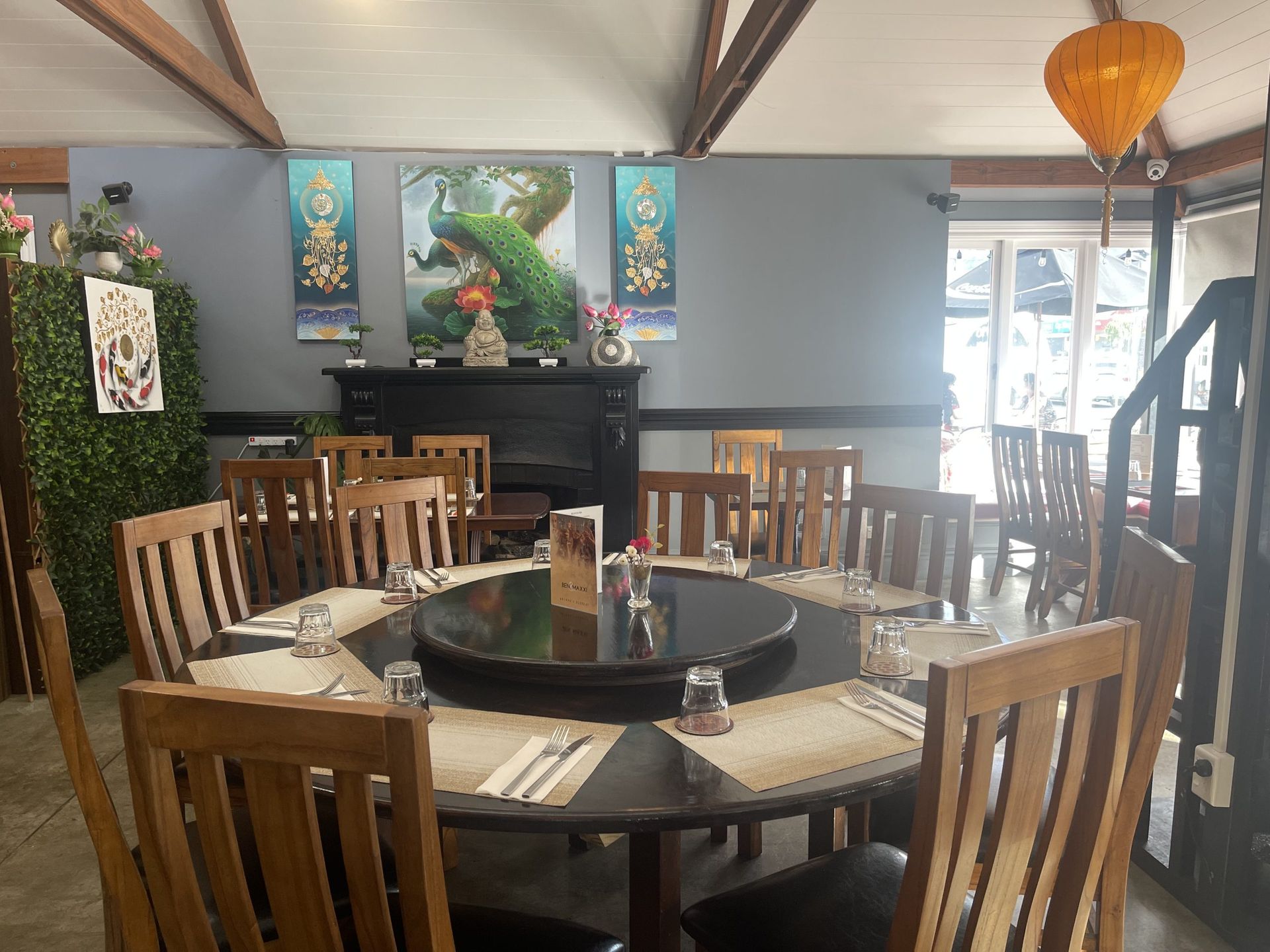 A restaurant with a round table and wooden chairs.