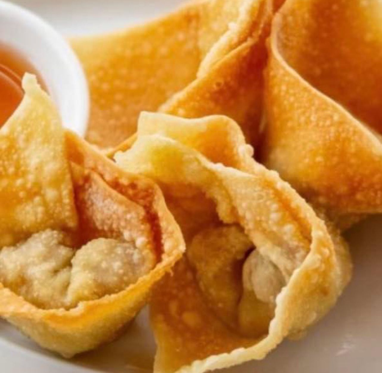 A white plate topped with fried wonton wrappers and dipping sauce