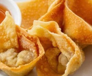 A close up of fried wonton wrappers with dipping sauce on a plate.