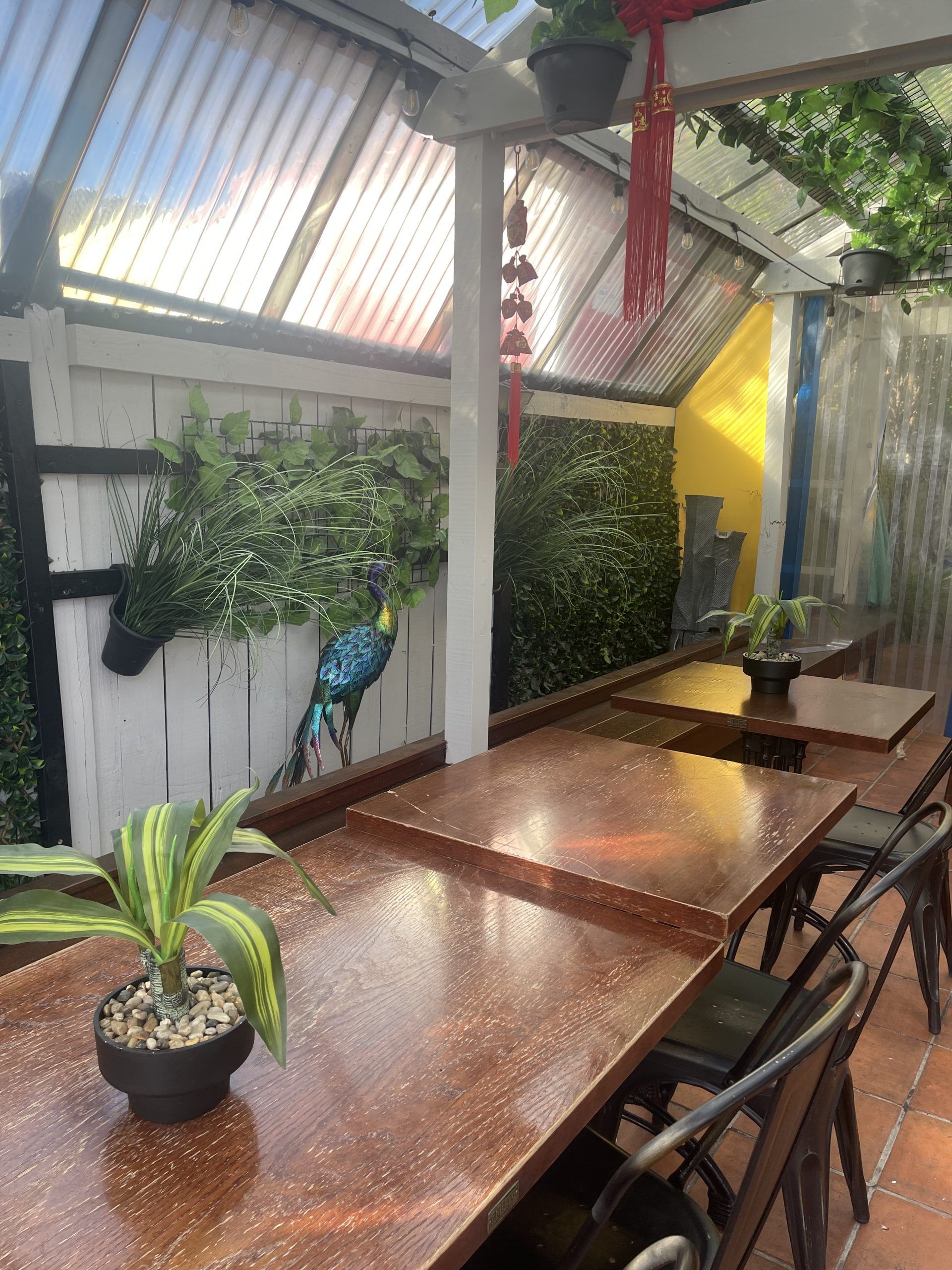 A row of tables with potted plants on them in a restaurant.