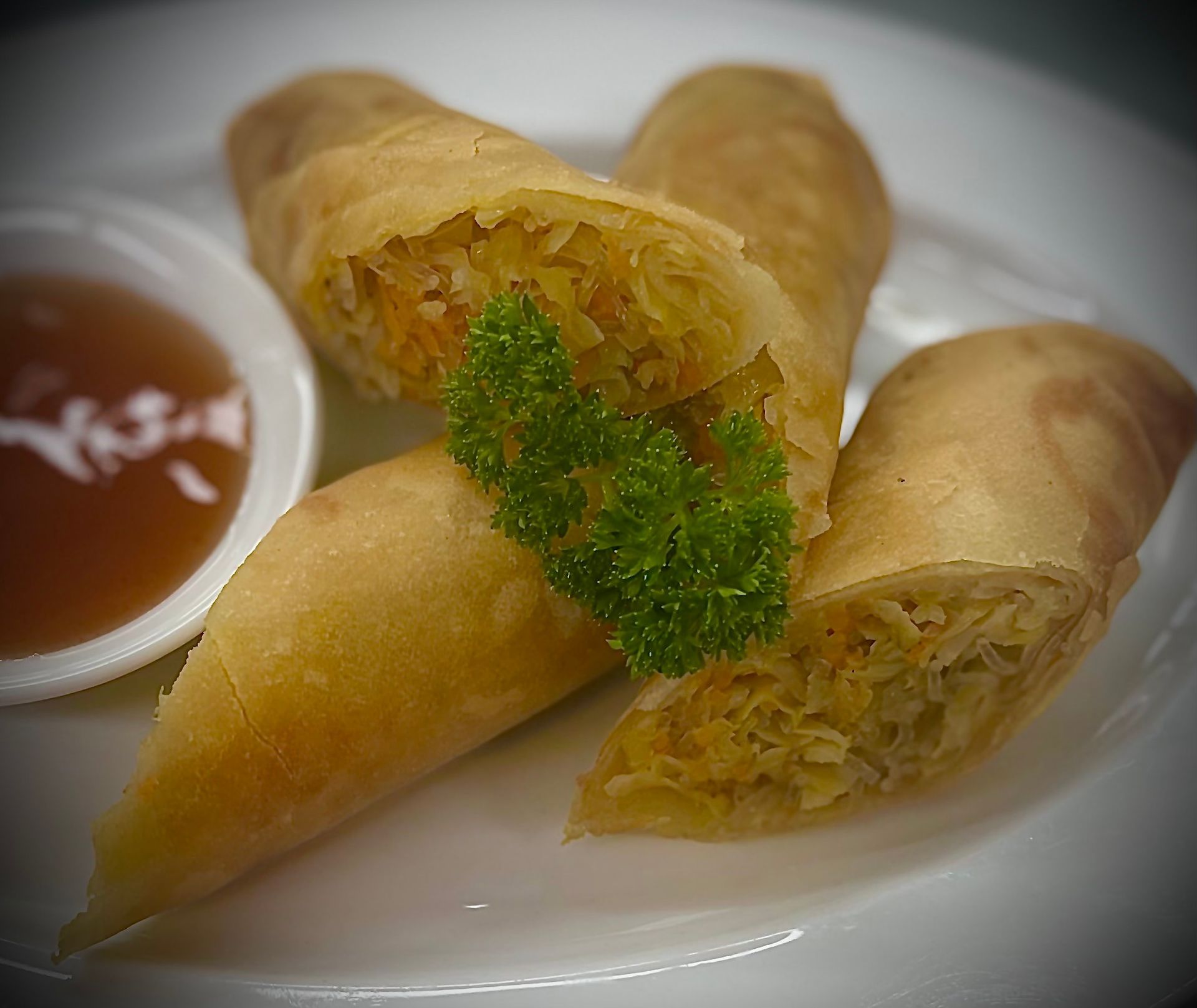 A close up of three spring rolls on a plate with dipping sauce.
