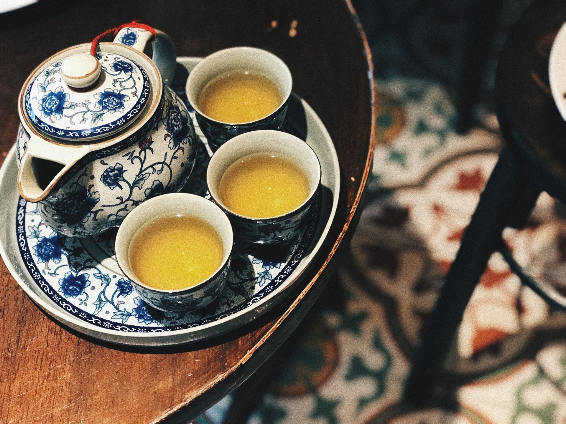 A teapot and four cups of tea are on a tray on a table.