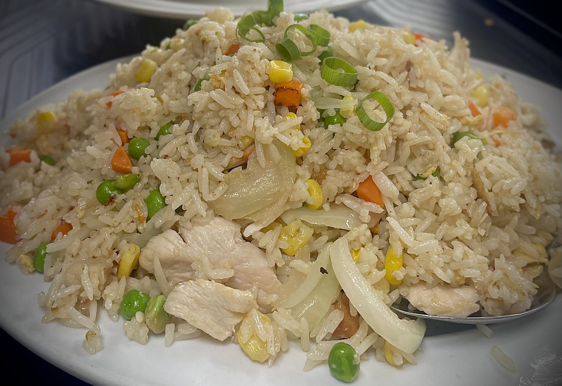 A white plate topped with rice and vegetables with a spoon in it