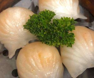 A close up of a bunch of dumplings with parsley on top.