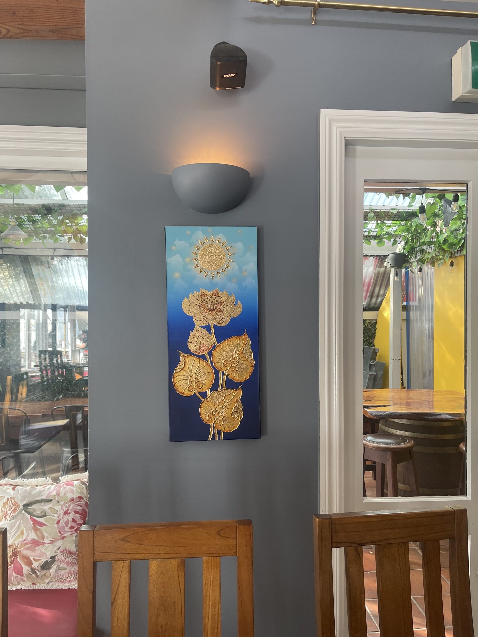 A painting of flowers hangs on a wall in a restaurant