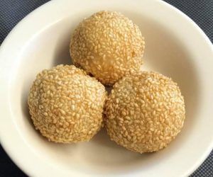 Three sesame seed balls are in a white bowl.