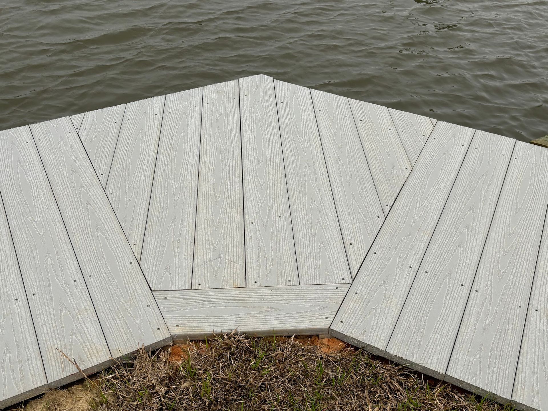 A gray, wooden dock extends into water.