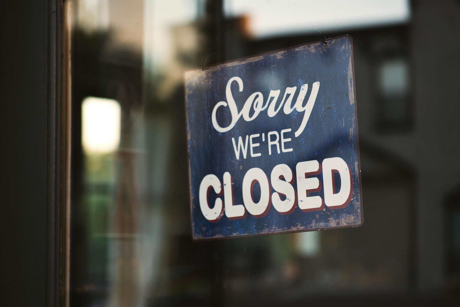 A sorry we 're closed sign is hanging on a glass door.