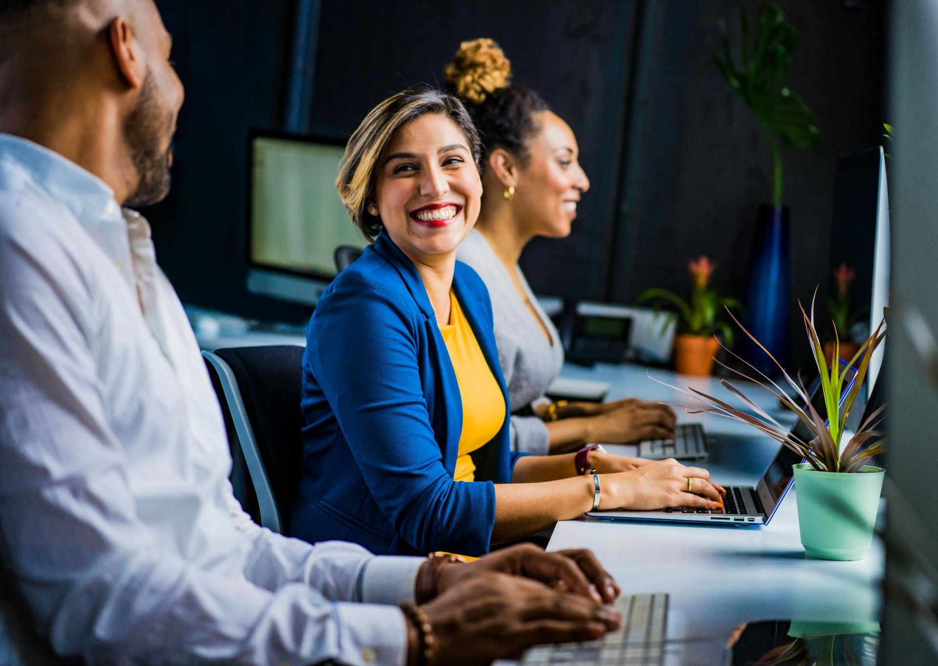 A group of people are sitting at desks in front of computers.