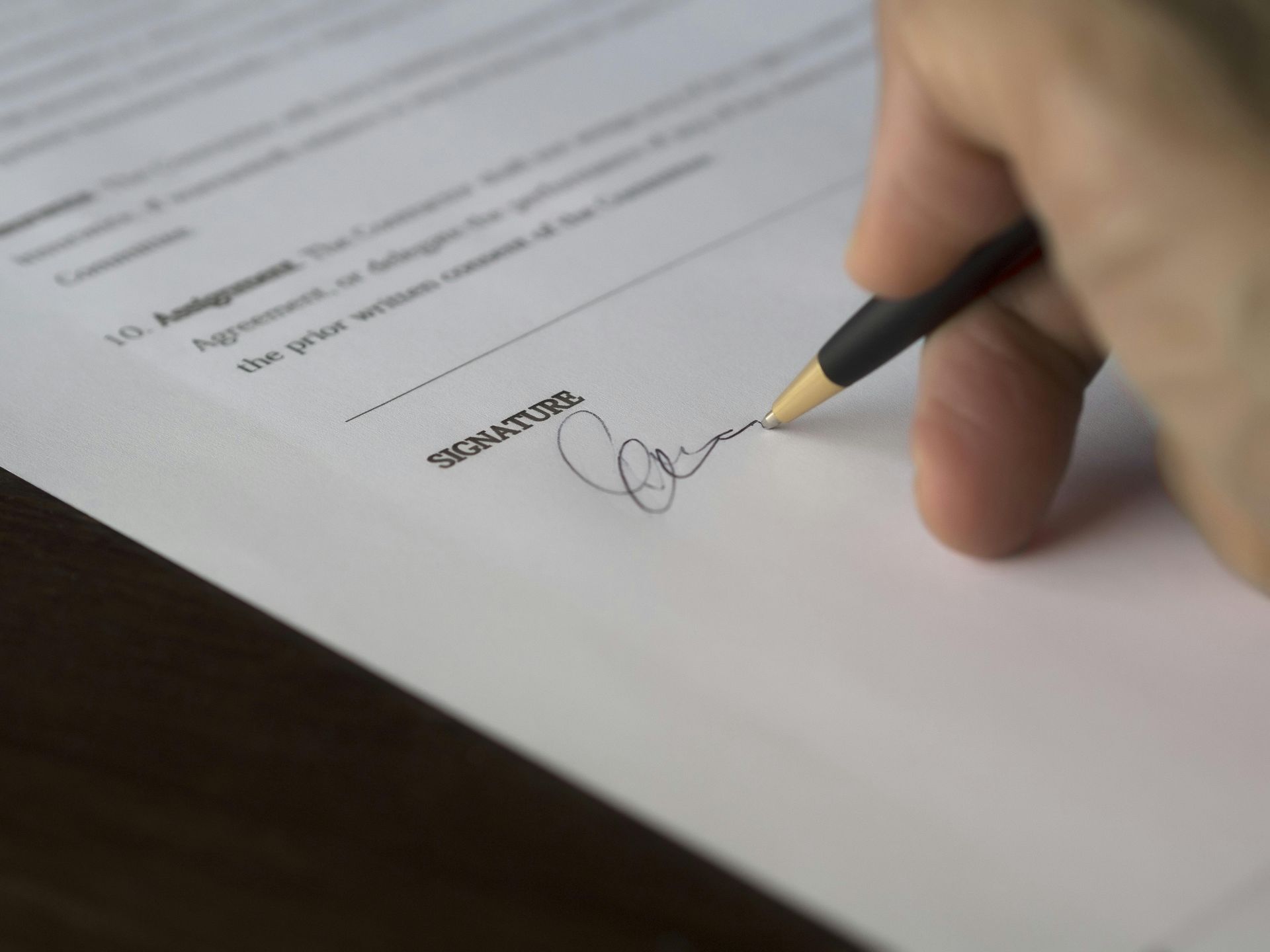 A person is signing a document with a pen.