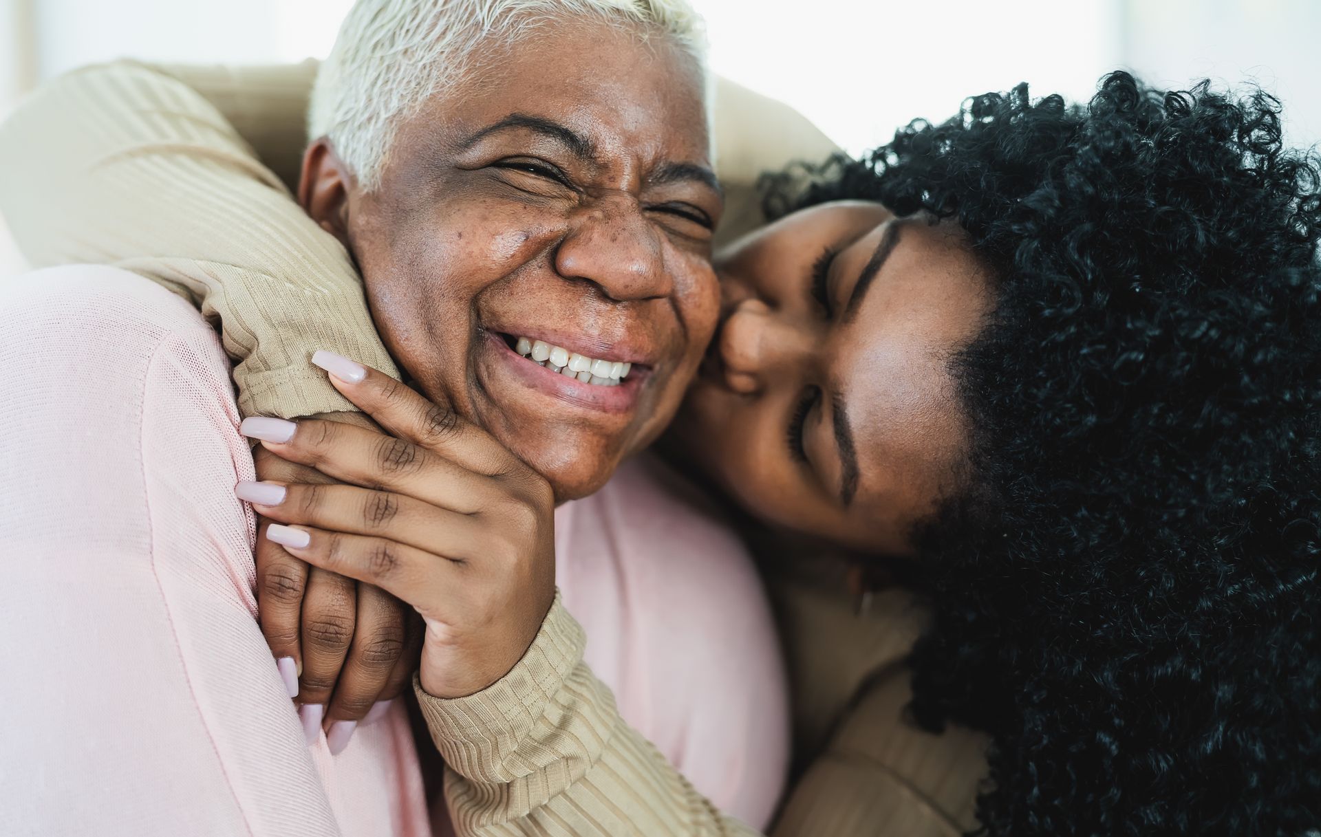 An older woman is being kissed on the cheek by a younger woman.