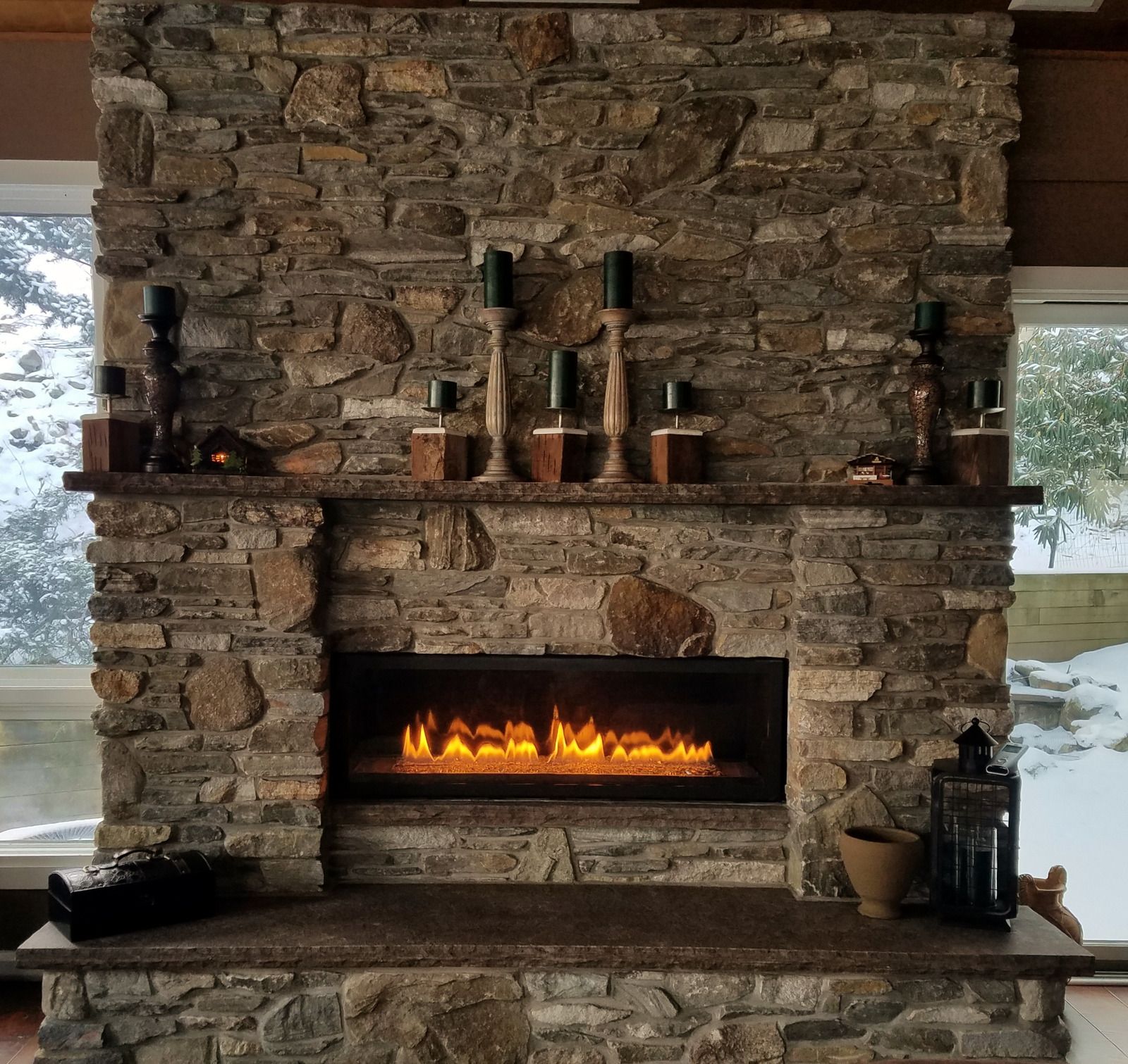 A stone fireplace with candles on the mantle