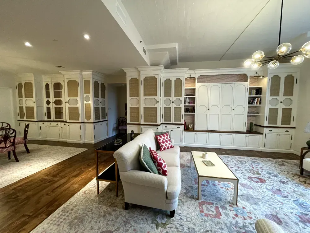 Living room with white cabinets, beige couch, patterned rug, and gold chandelier.