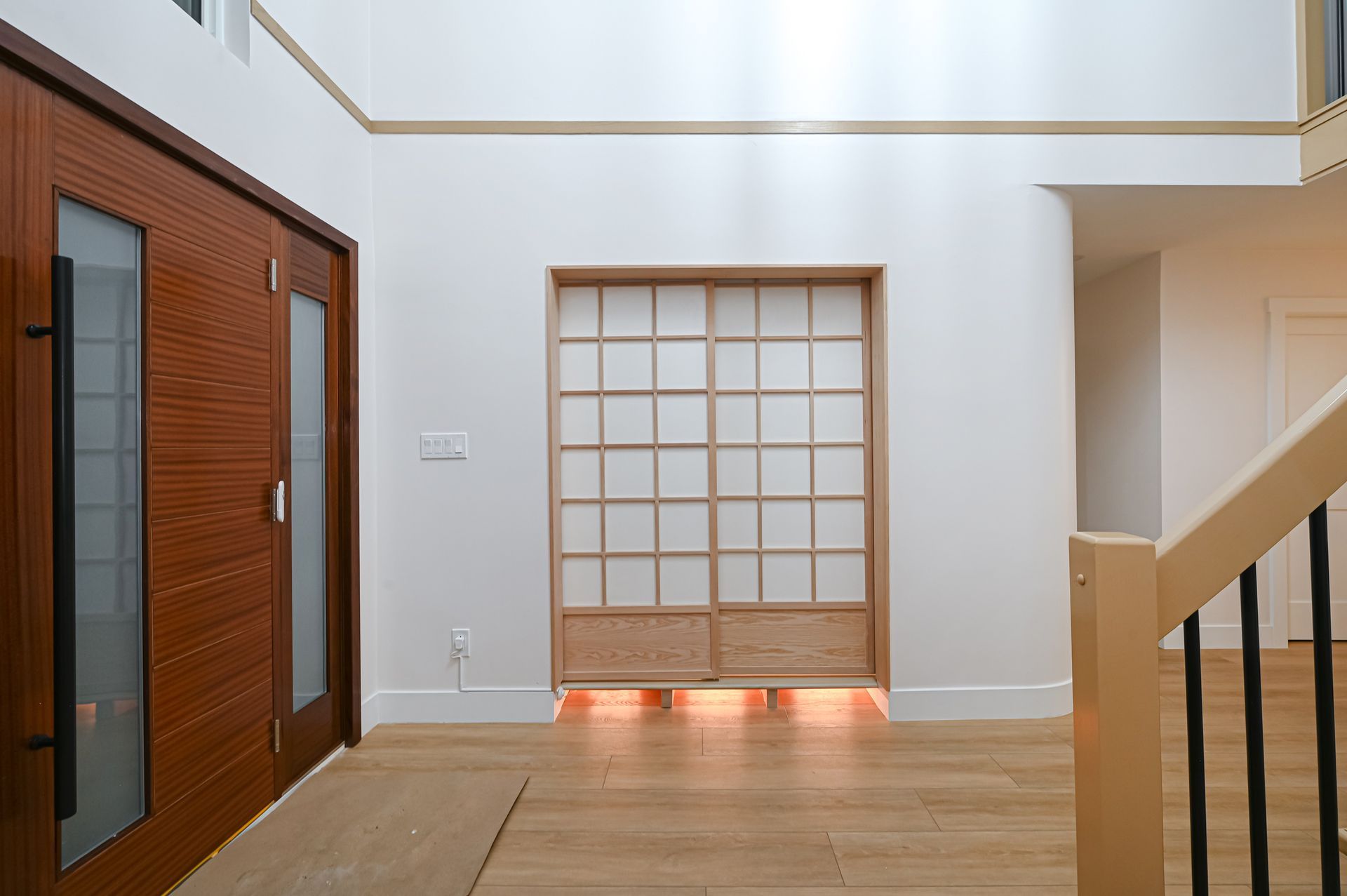Modern luxury entryway with wood door, light floors, and Japanese shoji screen