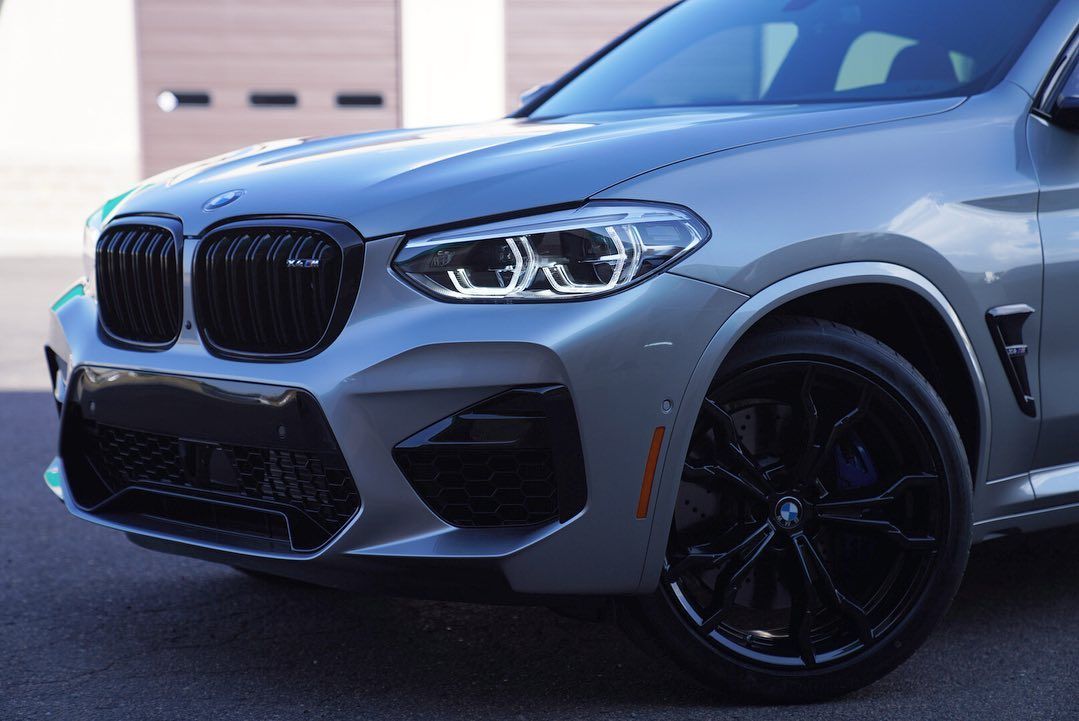 Silver BMW X3 M SUV, black grill and wheels, parked outside.