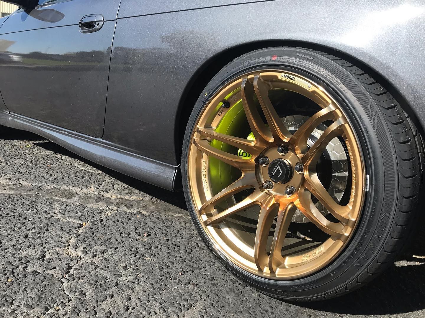 Gray car with gold rims and lime green brake calipers.