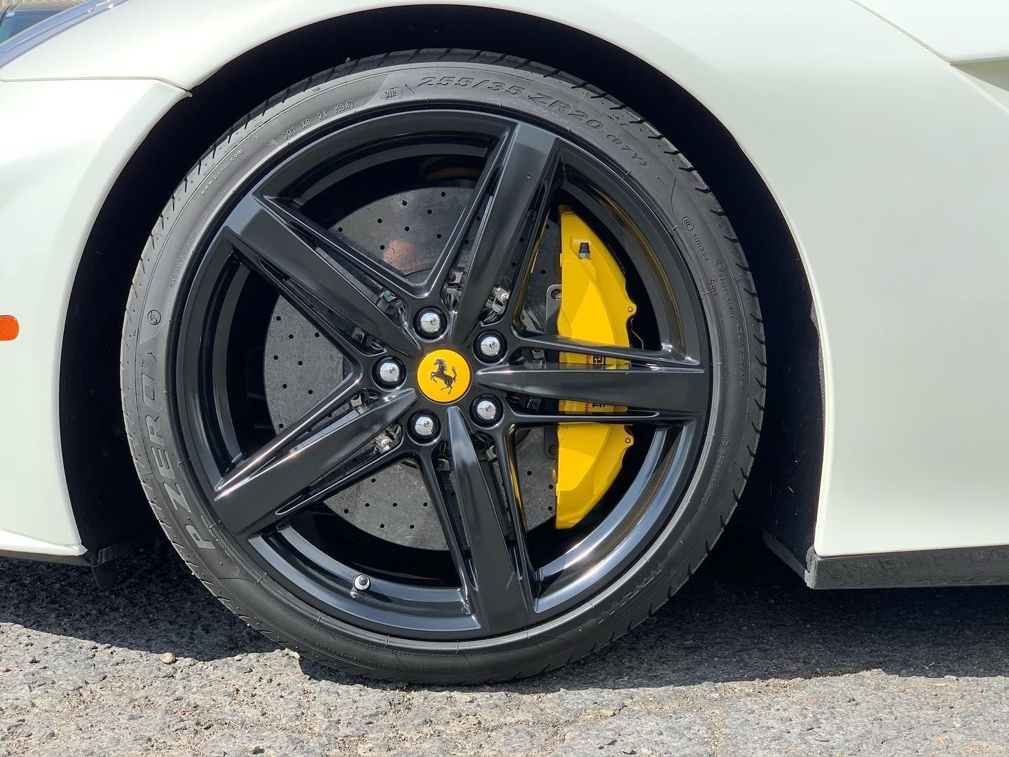 Black Ferrari wheel with yellow brake caliper.