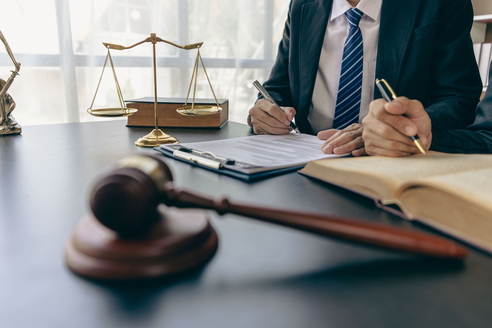 A lawyer is sitting at a desk with a gavel and scales of justice.