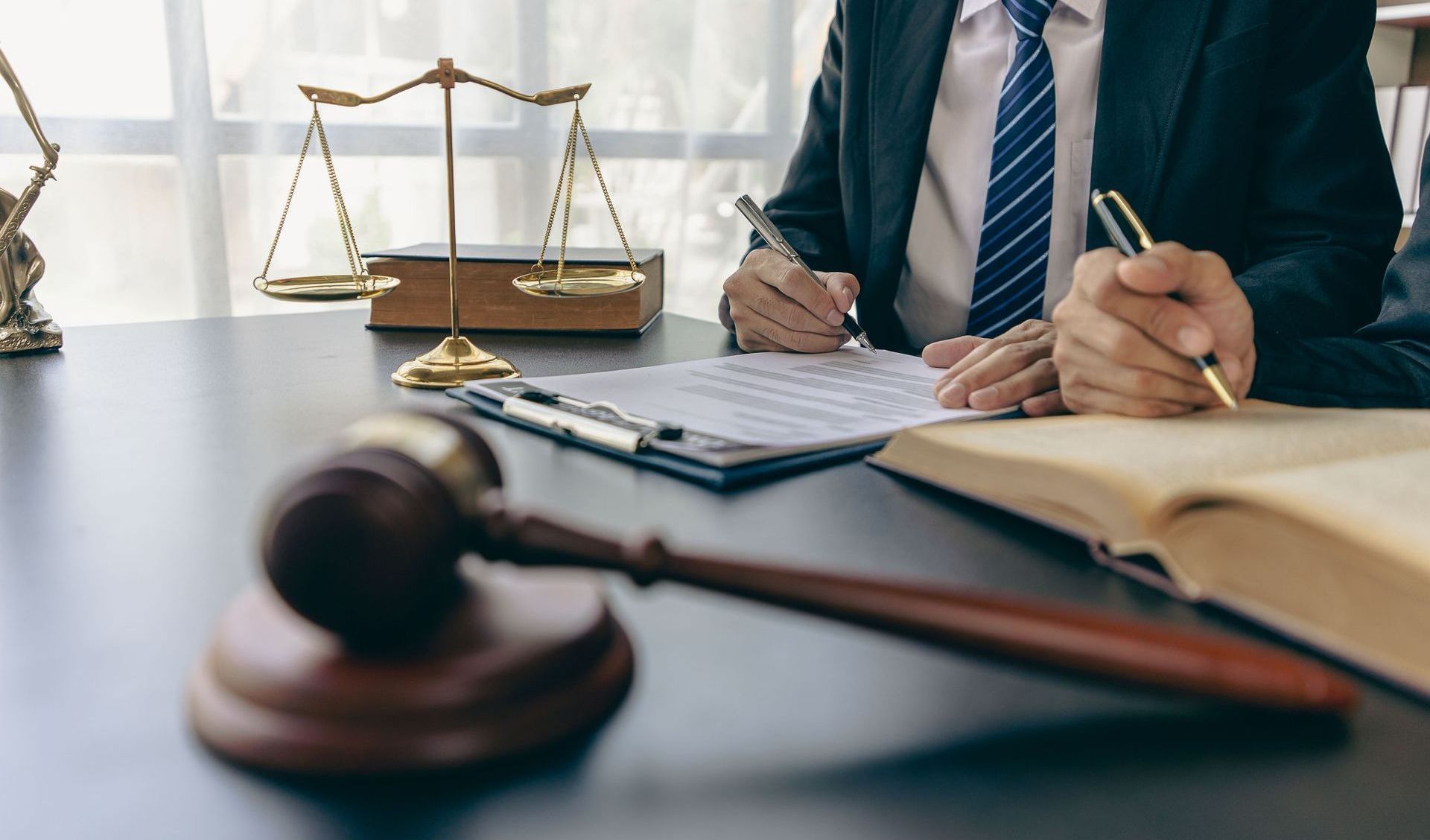 A lawyer is sitting at a desk with a gavel and scales of justice.