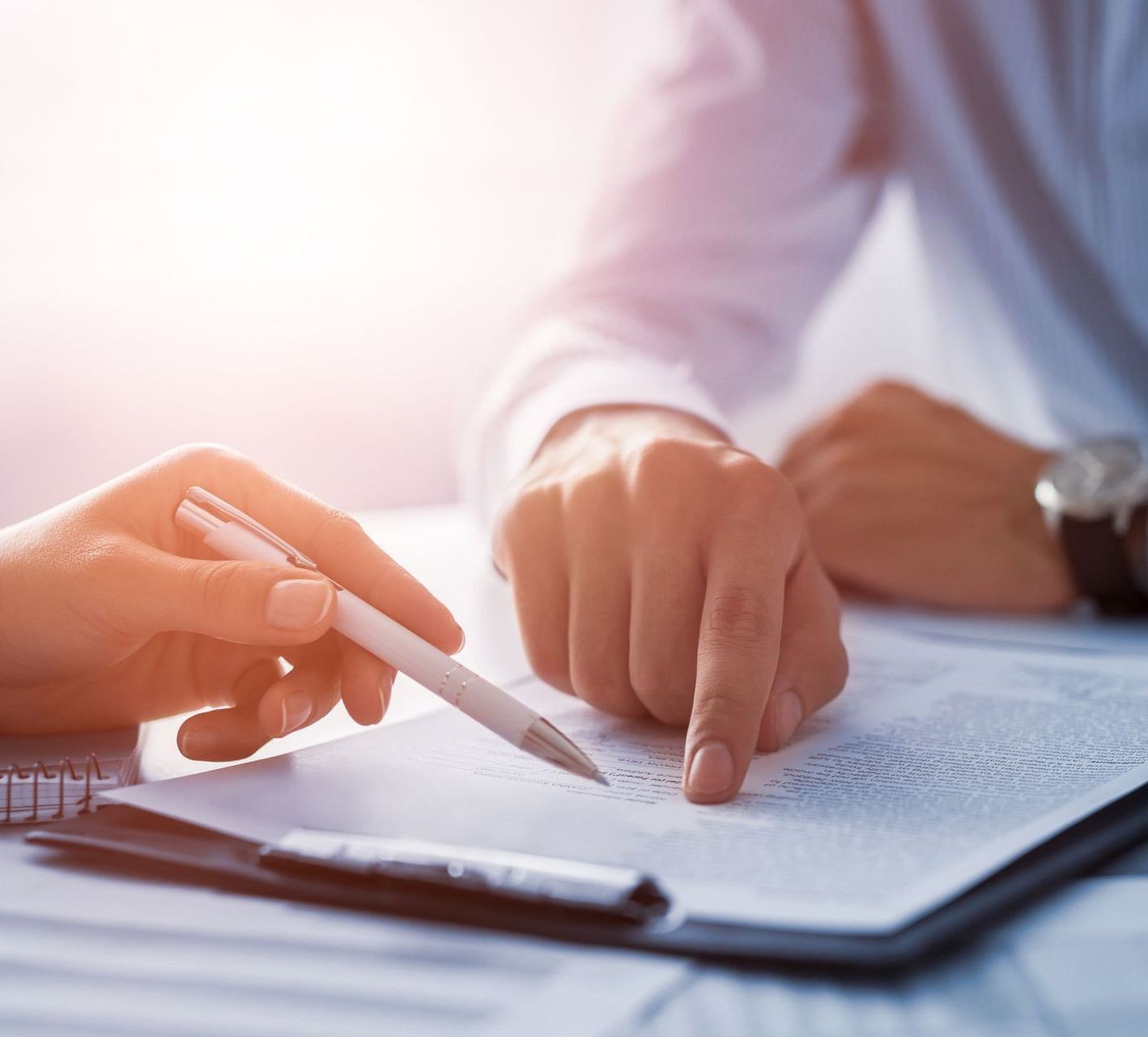 A man and a woman are signing a document on a clipboard.