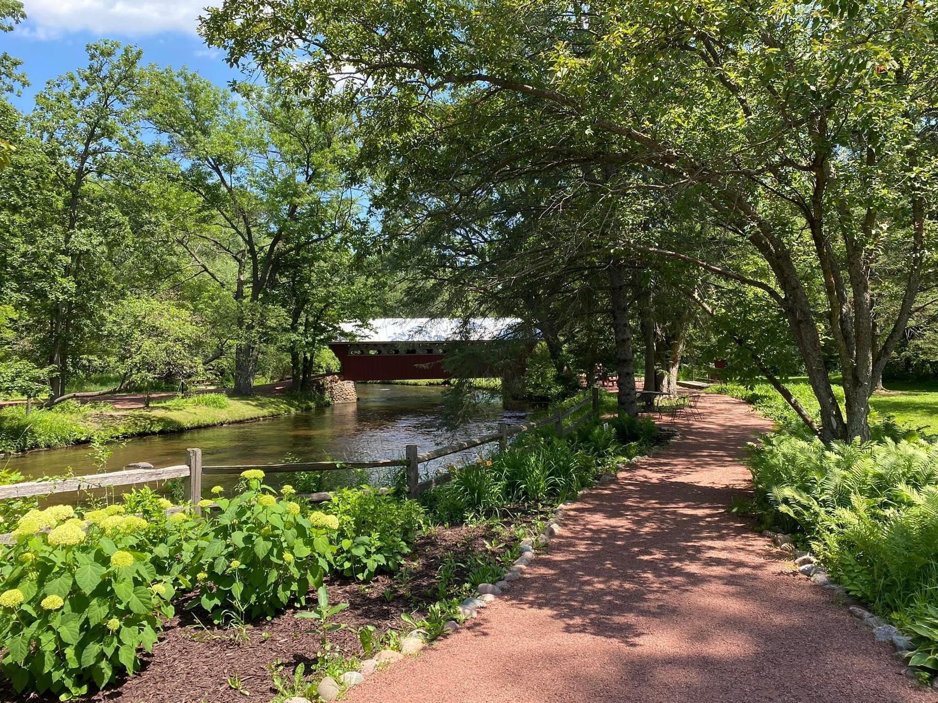 A path leading to a bridge over a river surrounded by trees.