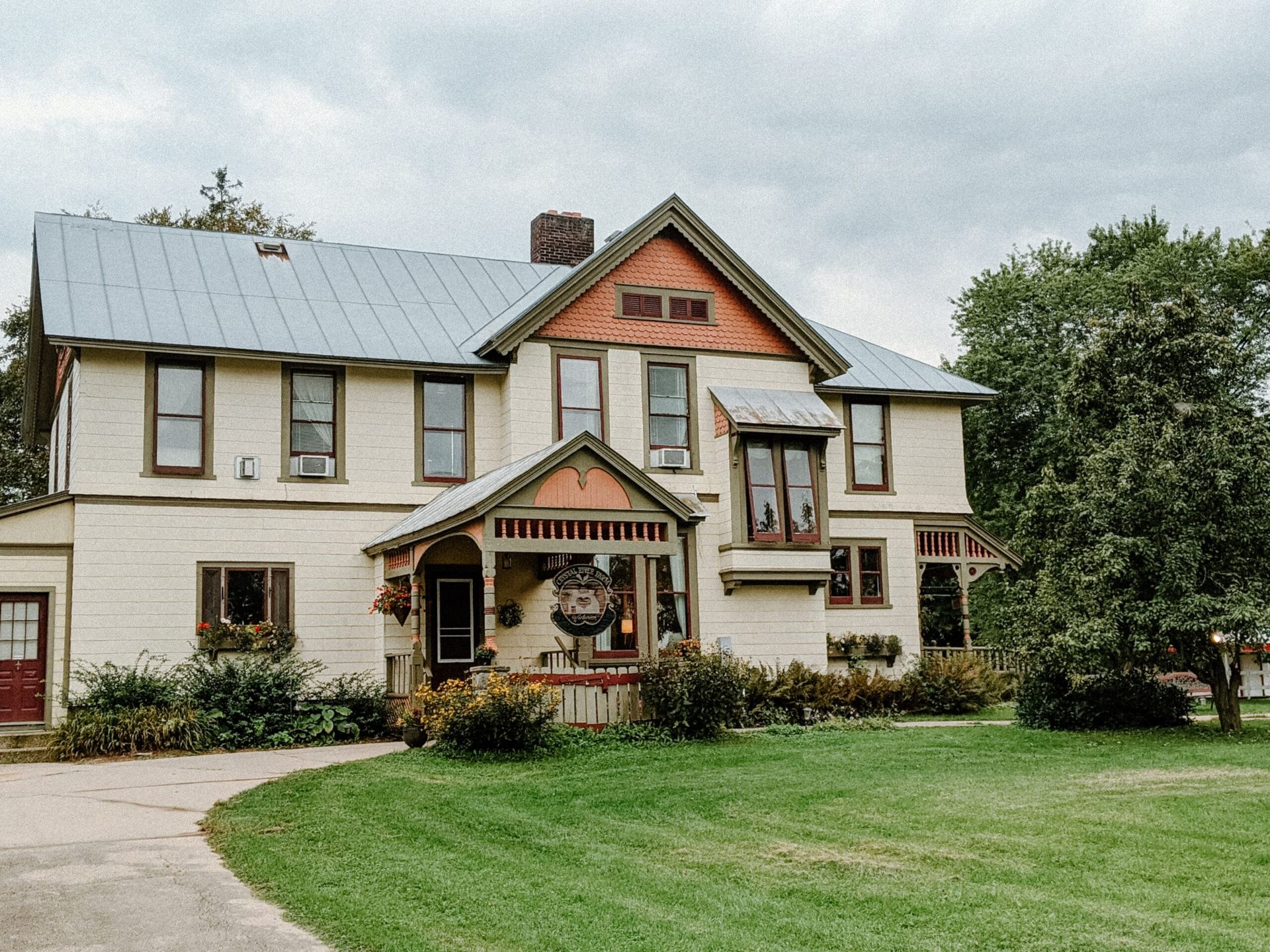 A large white house with a metal roof is sitting on top of a lush green field.