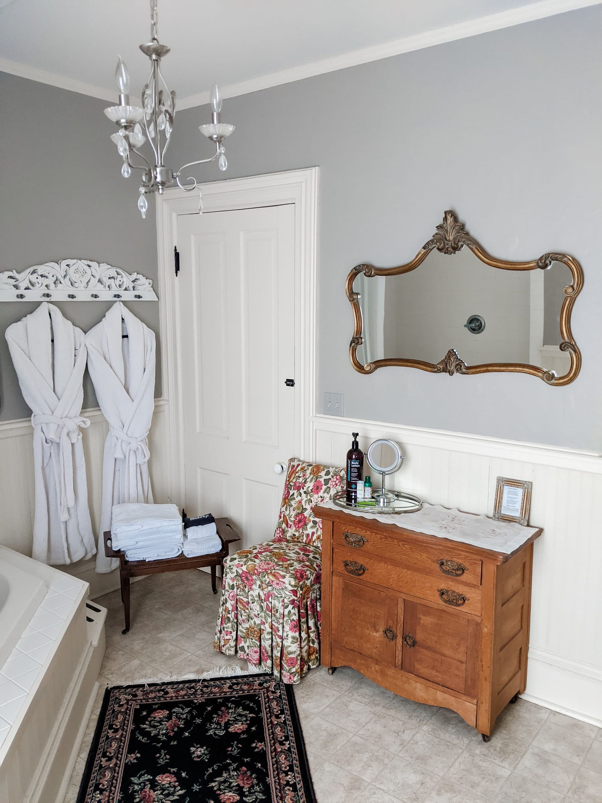 A bathroom with a dresser , chair , and mirror