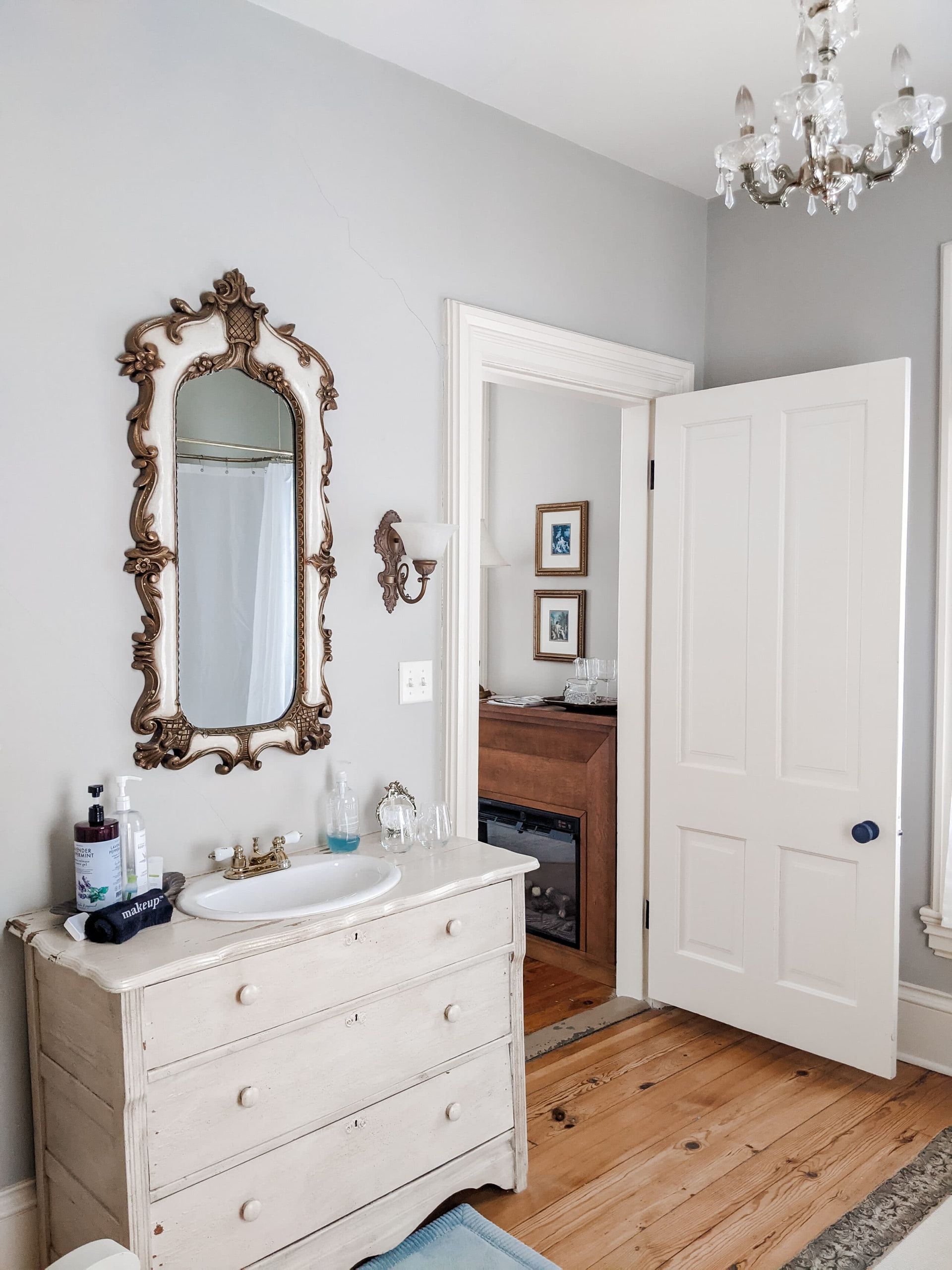 A bathroom with a dresser , sink and mirror