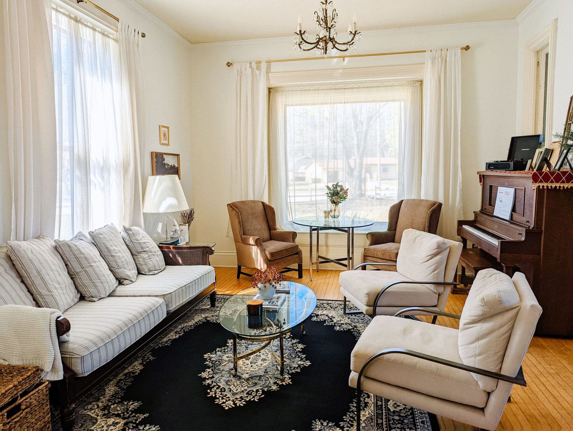 A living room with a couch , chairs , and a piano.