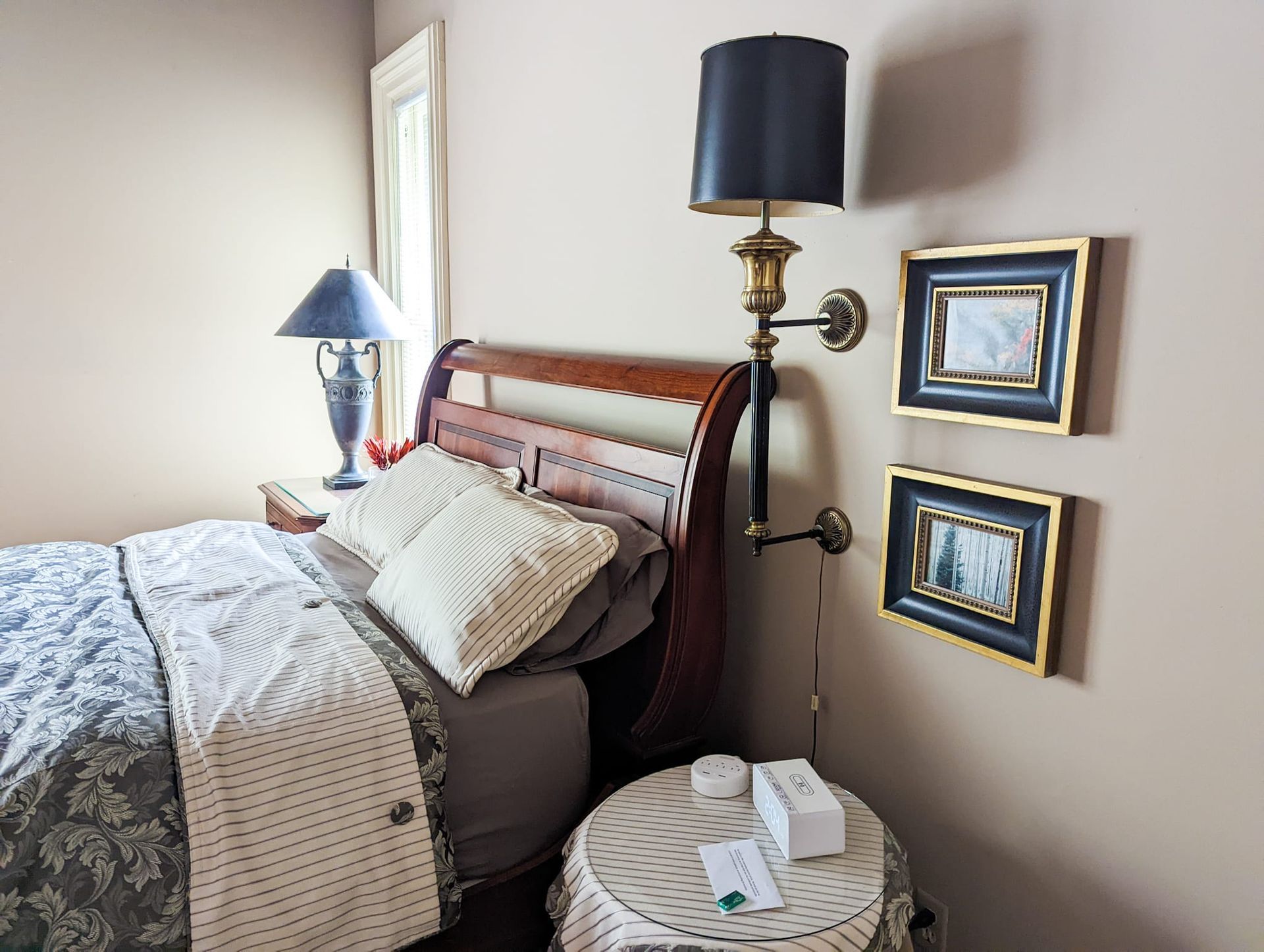 A bedroom with a bed , nightstand , lamp and pictures on the wall