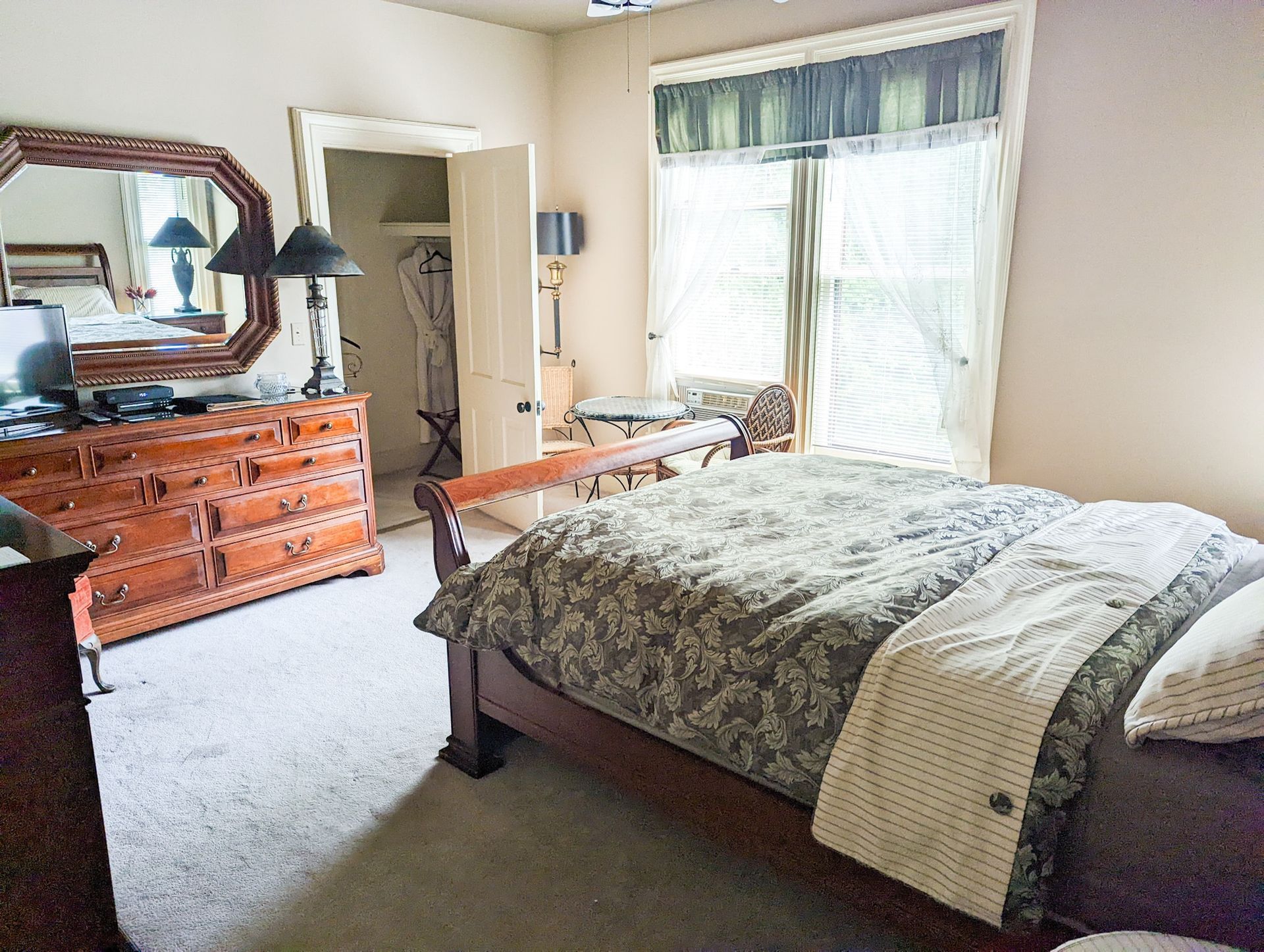 A bedroom with a bed , dresser and mirror