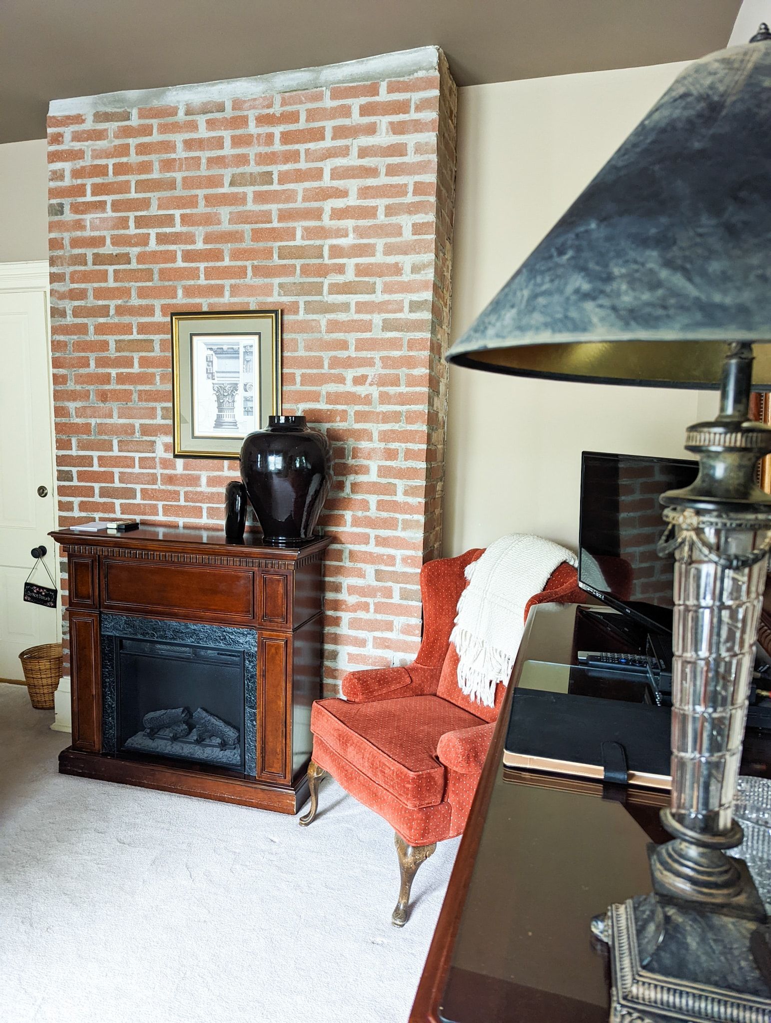 A living room with a fireplace , chair and lamp