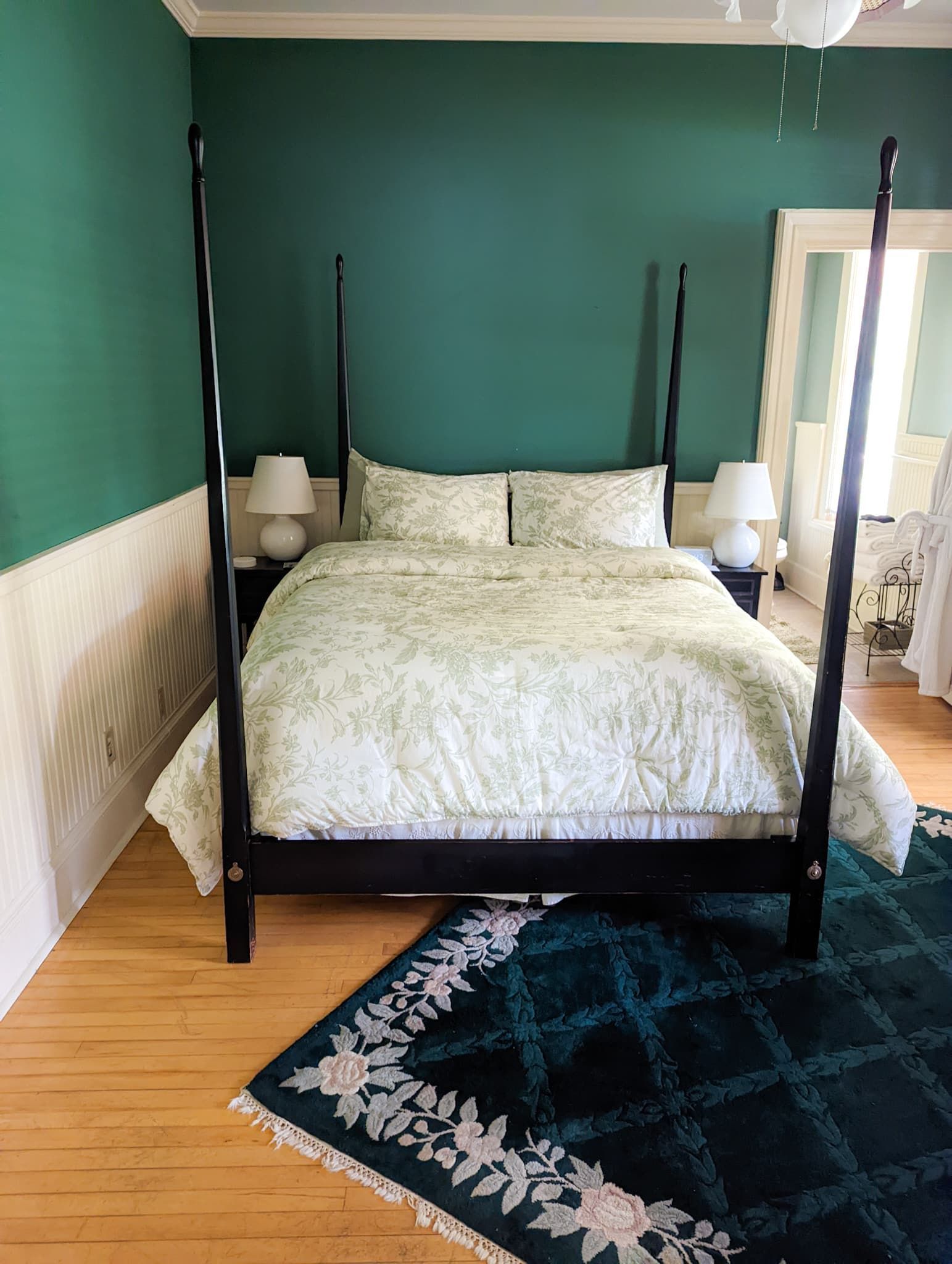 A bedroom with green walls and a four poster bed.