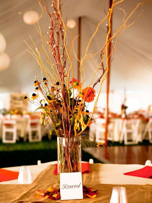 A vase filled with flowers and branches is on a table.