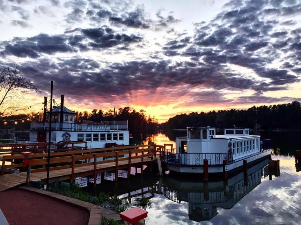 A boat is docked at a dock on a lake at sunset.