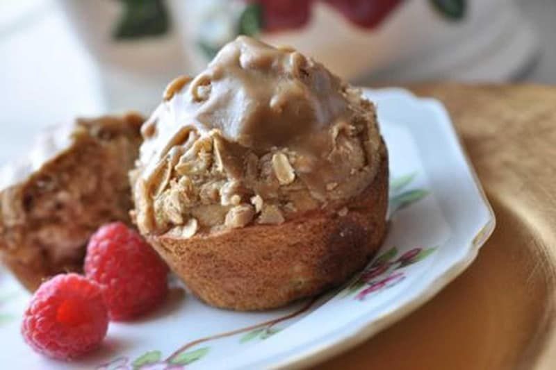 A close up of a muffin on a plate with raspberries.