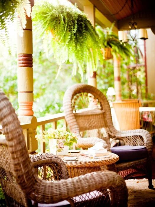 There are two wicker chairs and a table on the porch.