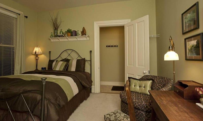 A bedroom with a bed , chair , desk and lamp