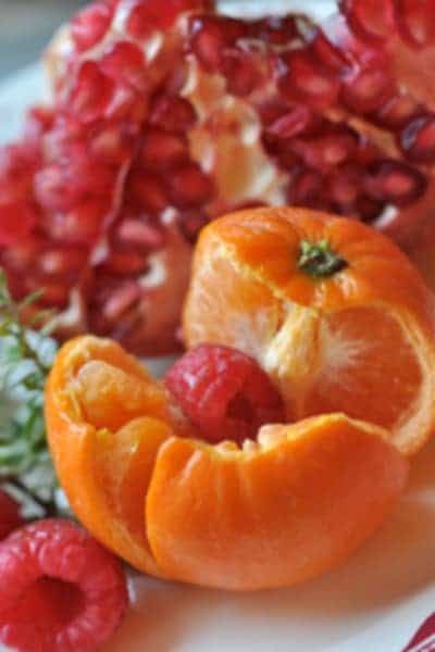 A white plate topped with raspberries and oranges