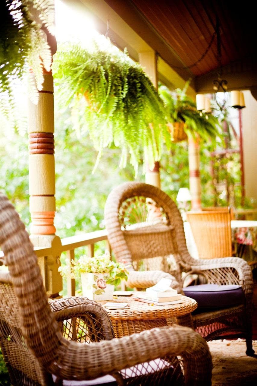 There are wicker chairs and a table on the porch.