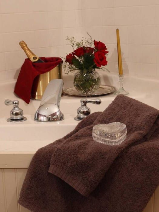 A bathtub with a bottle of champagne and a vase of flowers