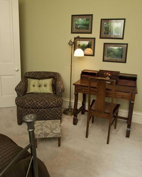 A room with a chair a desk and a lamp